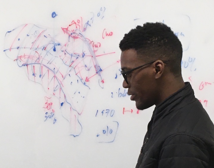 photograph of T Oguns in profile in front of a whiteboard